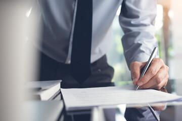 businessman signing contract or proofing paper document while working in office
