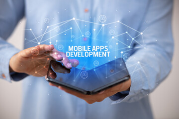 Businessman holding a foldable smartphone with MOBILE APPS DEVELOPMENT inscription, new technology concept
