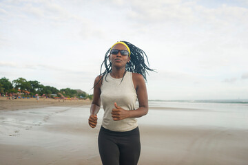 african American woman running on the beach - young attractive and athletic black girl training outdoors doing jogging workout at the sea in fitness and healthy lifestyle concept