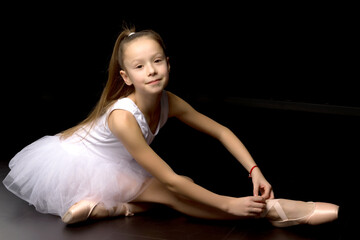 Fototapeta na wymiar Girl ballerina puts on pointe shoes. The concept of dancing.