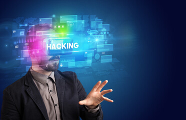 Businessman looking through Virtual Reality glasses with HACKING inscription, innovative security concept