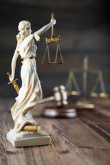 Law symbols composition. Themis statue, judge’s gavel and scale of justice on rustic wooden desk.