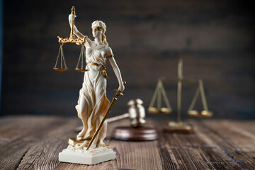 Law symbols composition. Themis statue, judge’s gavel and scale of justice on rustic wooden desk.