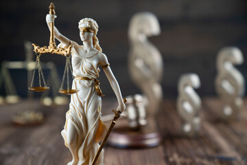 Law symbols composition. Themis statue, judge’s gavel and scale of justice on rustic wooden desk.