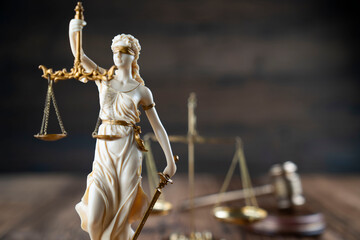 Law symbols composition. Themis statue, judge’s gavel and scale of justice on rustic wooden desk.