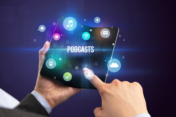 Businessman holding a foldable smartphone with PODCASTS inscription, social media concept