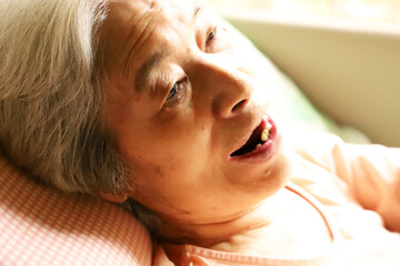 介護用ベッドでくつろぎながら歌を歌うシニア女性