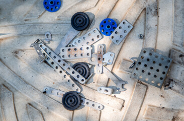 A boy collects parts of a metal constructor in the open air and develops motor skills