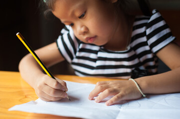 A four-year-old girl who is serious about writing homework.