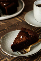 Moist Ginger Chocolate cake sliced and sprinkled with sea salt and cup of tea on wooden table. Selective focus
