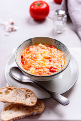 Vegetarian spicy tomato rice soup on grey concrete background. Selective focus