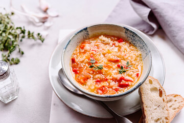 Vegetarian spicy tomato rice soup on grey concrete background. Selective focus