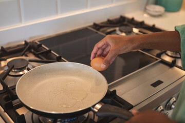 Mid section of woman cooking eggs in the kitchen