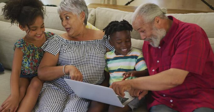 Grandparents and grandchildren using laptop at home