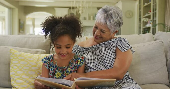 Grandmother and granddaughter reading book at home