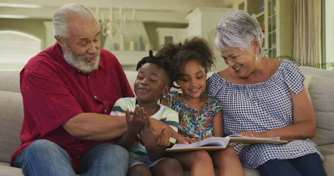 Grandparents And Grandchildren Reading Book At Home