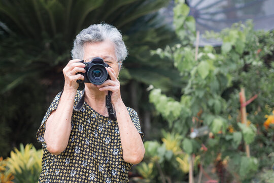 Elderly woman shooting photo by digital camera at garden