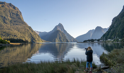 Asian woman looking at view with beautiful scenic of milford sound in fiordland national park new zealand.