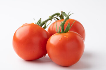 Fresh tomatoes on a green stem on white