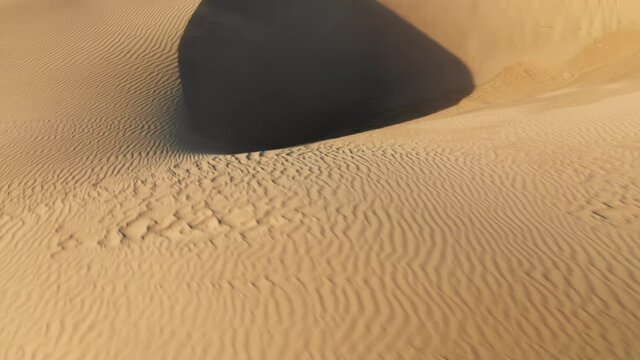 Unique aerial view from drone flying low over the scenic landscape of massive beige dunes at sunset. Wild desert nature, USA. 4K drone view on the abstract wavy shape and pattern on golden sand hills