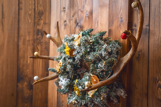 Deer antlers decorated with bells, Christmas wreath with frost, dried oranges