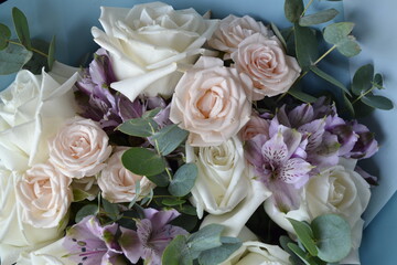 flower bouquet in cold colors with white and peach roses in blue packaging