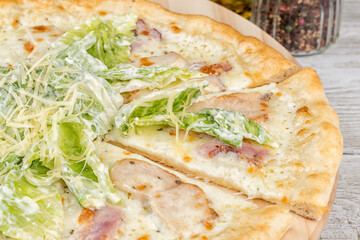 Caesar pizza with sliced piece on a round board