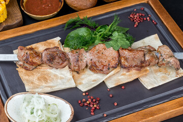 One kebab with pita bread on a black, slate board