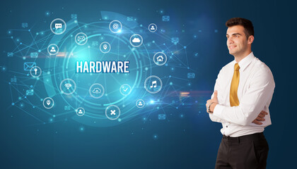 Businessman thinking in front of technology related icons and HARDWARE inscription, modern technology concept