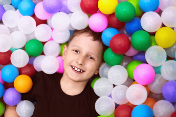 Fototapeta na wymiar boy in entertainment center. happy child has fun among colorful soft balls.