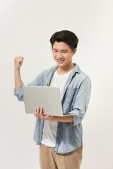Happy young Asian man carrying laptop computer and raising his fist doing yes gesture isolated on white background
