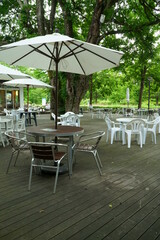 Cafe terrace with white umbrellas and large trees