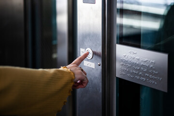 エレベーターのボタンを押す女性