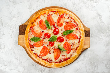 Round pizza with tomatoes and cheese on a wooden board