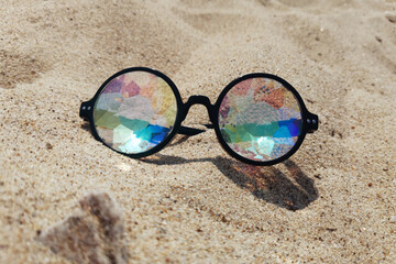 Fototapeta na wymiar designer glasses with lenses kaleidoscope in the sand