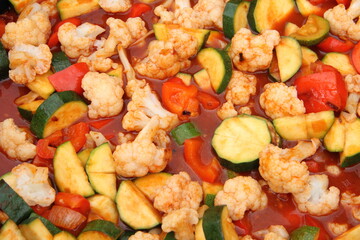 a pan with cauliflower, zucchini, peppers and tomato