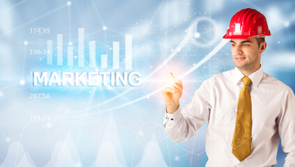 Young businessman with helmet drawing MARKETING inscription, modern business technology concept