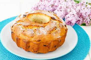 Delicious homemade raisin cupcake, lilac flowering branch.