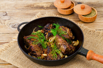 Cast-iron frying pan on wooden table with fried liver.