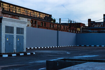 Empty closed new parking near the old industrial area and the walls of the old factory at sunset.