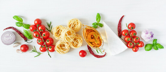 Italian pasta ingredients for cooking. Raw pasta, cheese, vegetables, spices and herbs top view on white wooden background.