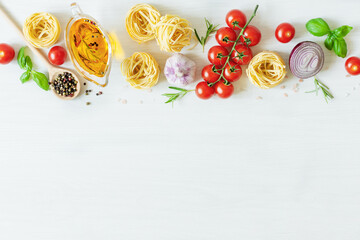 Naklejka na ściany i meble Italian pasta ingredients for cooking. Raw pasta, vegetables, spices and herbs top view on white wooden background.