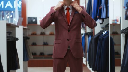 Stylish businessman man trying on a suit jacket in shop