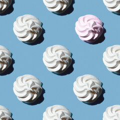 Seamless pattern is a white marshmallow or meringue and one pink marshmallow isolated on a classic blue background