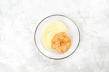 Fried cutlet with crushed potatoes in a white plate
