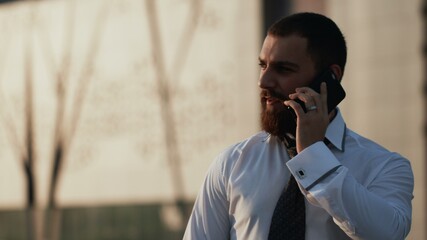 Attractive caucasian businessman using smartphone outdoors