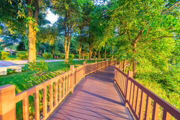 Obraz premium Outdoor park square with brick walkways and wooden paths at sunrise and sunset.