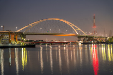 水面に浮かぶ新浜寺大橋と工場の光