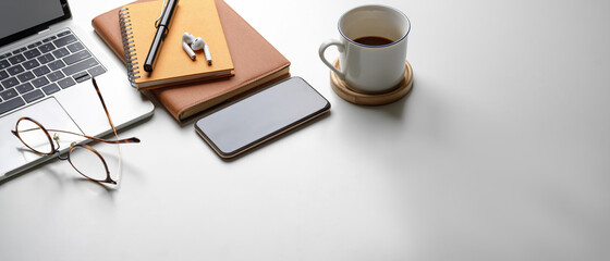 Portable workspace with copy space, smartphone, laptop, glasses, coffee cup and stationery