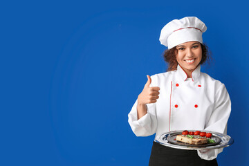 Female African-American chef with tasty dish on color background